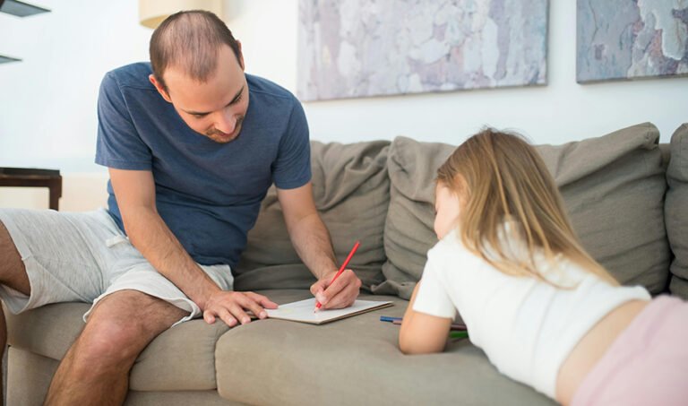 Un padre realiza una tarea escolar junto a su hija.