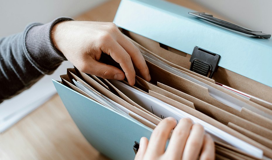 Un trabajador consulta documentación en una carpeta clasificadora.