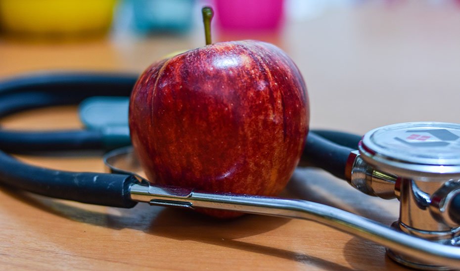 Una manzana junto a un fonendoscopio.