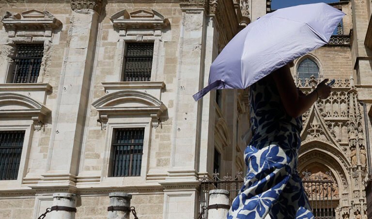 Una turista se protege del con una sombrilla mientras pasea ante la Catedral de Sevilla. (Foto: EFE)