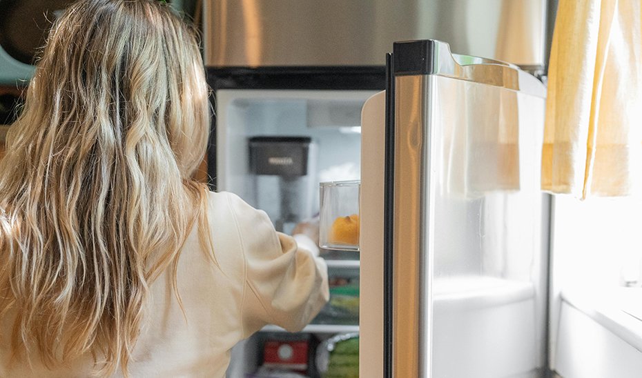 Una joven comprueba el estado de los alimentos en el frigorífico.