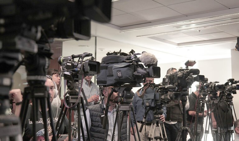 Cámaras de televisión apostadas para cubrir un acto informativo.